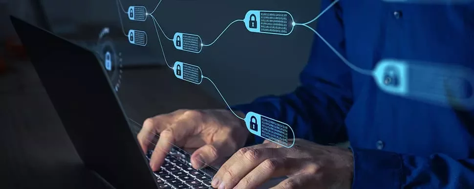 Hands typing on a laptop with digital blockchain icons overlay.