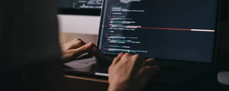 Person coding on a laptop with a dark-themed code editor.