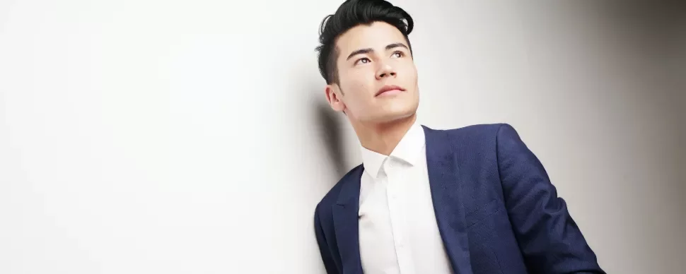 Person in a blue suit and white shirt gazing upwards against a light background.