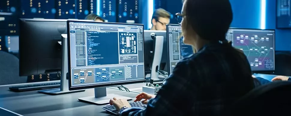 Person working at a computer with code on the screen in a tech office.