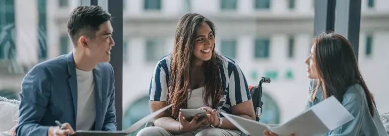 Three people having a discussion in an office setting.