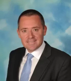 Person in a suit and tie with a blue sky background.
