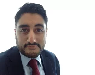 Person in a suit with a red tie, facing the camera against a bright background.