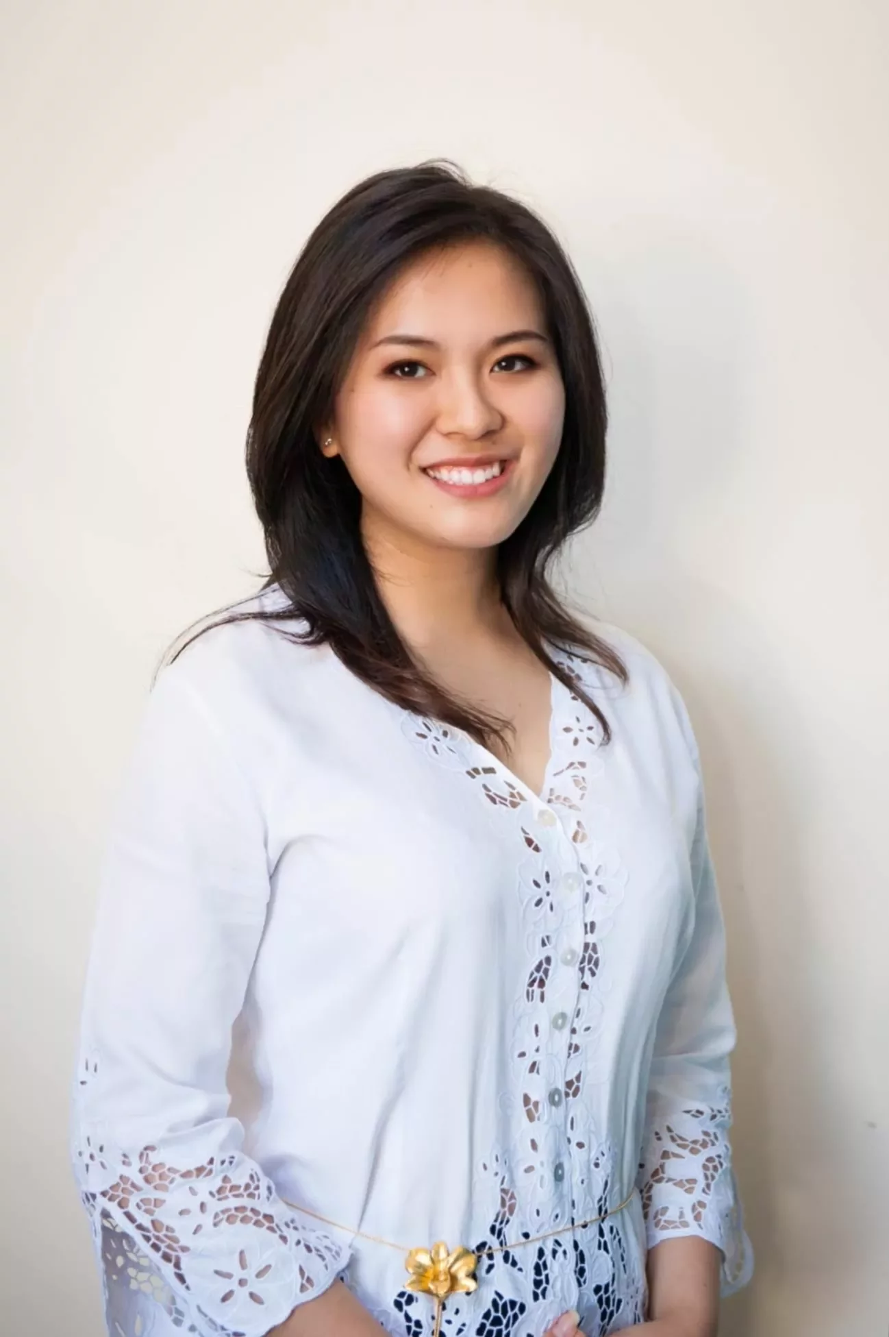 Person smiling in a white lace top against a light background.