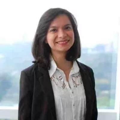 Person smiling in front of a window with a cityscape backdrop.
